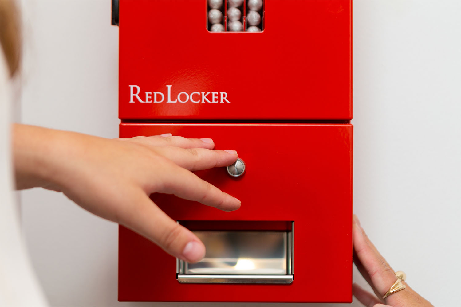 En hand sträcker sig mot ett rött plåtskåp med texten RedLocker.